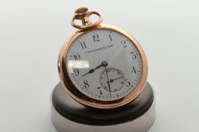A close up of a pocket watch on a white surface